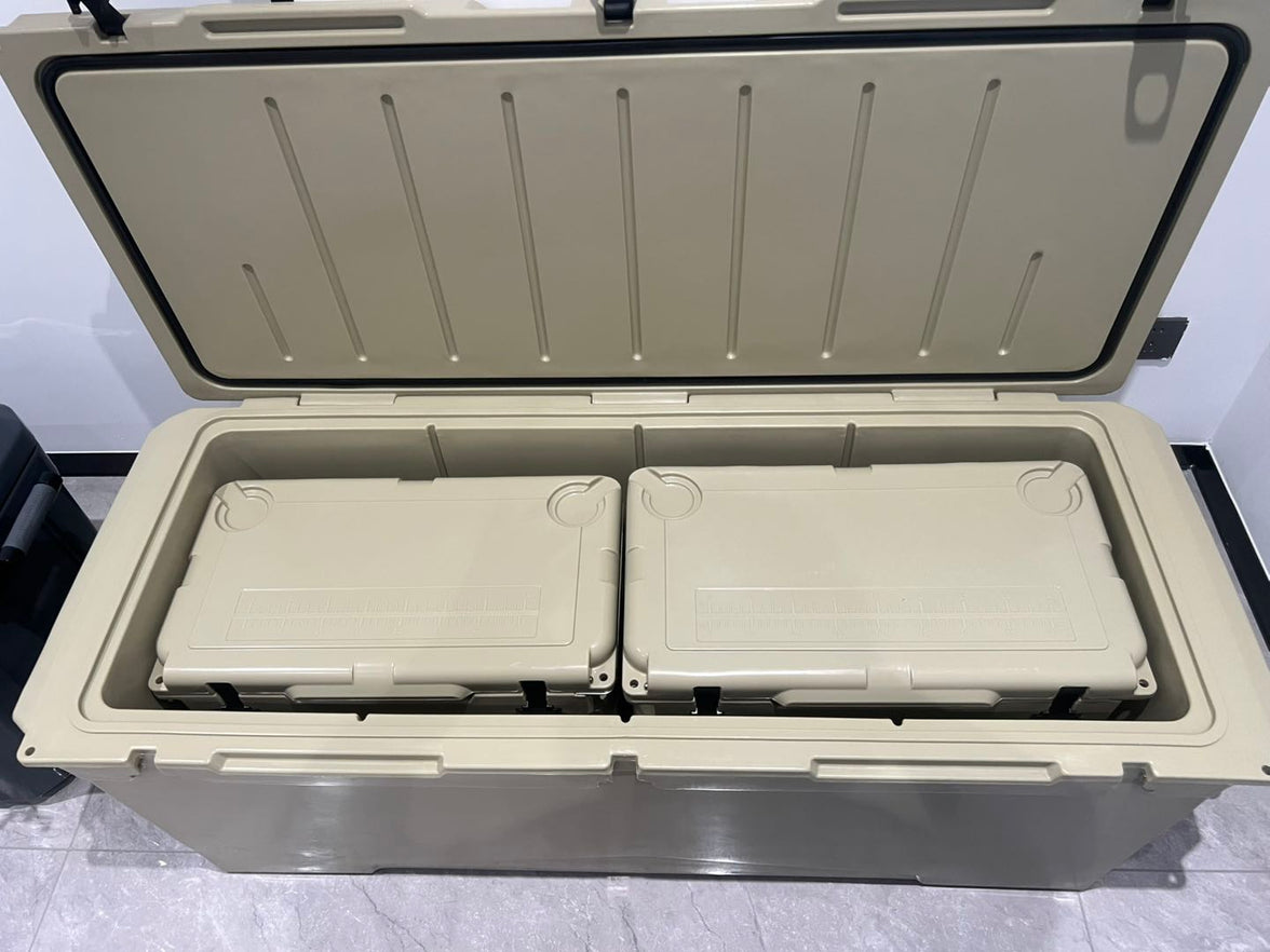 A large beige insulated cooler box with its lid open, showing two smaller matching cooler boxes nested inside on a gray tiled floor.
