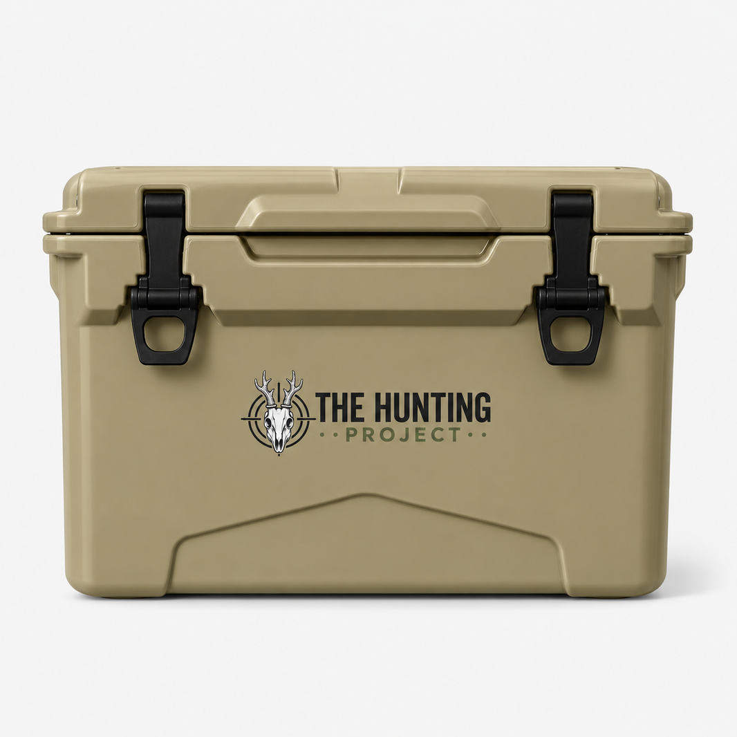 A tan hard-sided cooler with black latches and a printed logo reading 'THE HUNTING PROJECT' on the front, photographed against a clean white background.